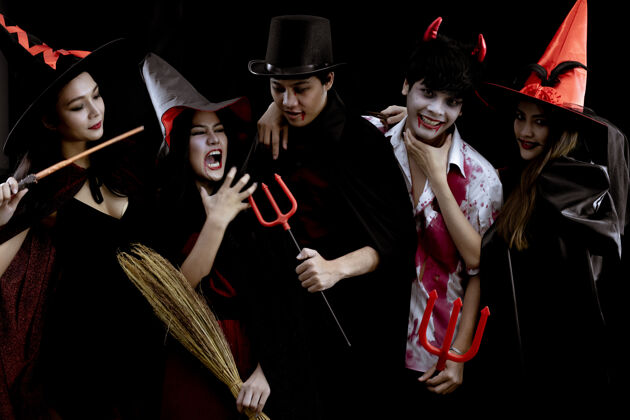 化妆在黑色的墙壁上 一群穿着服装的亚洲年轻人在万圣节派对上为万圣节时尚节构思…服装鬼魂 一群泰国年轻人的邪恶微笑影子青少年