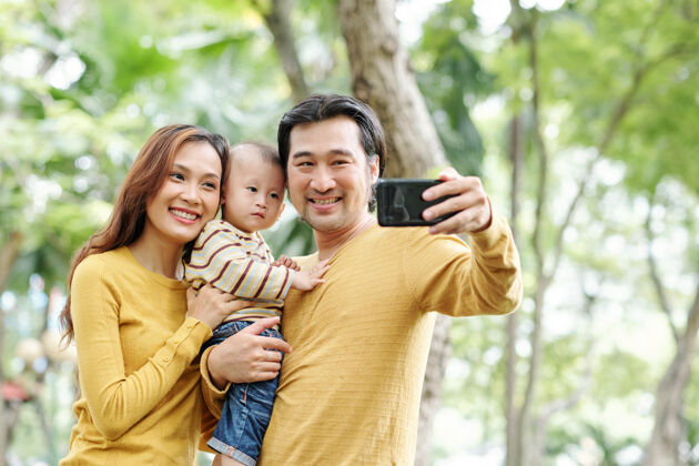 女人快乐积极的亚洲男人与他美丽的妻子和可爱的小儿子自拍手机孩子男人