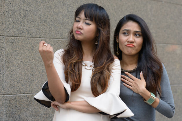 压力两位年轻的亚洲女商人在城市户外的合影闹市区道路爱情