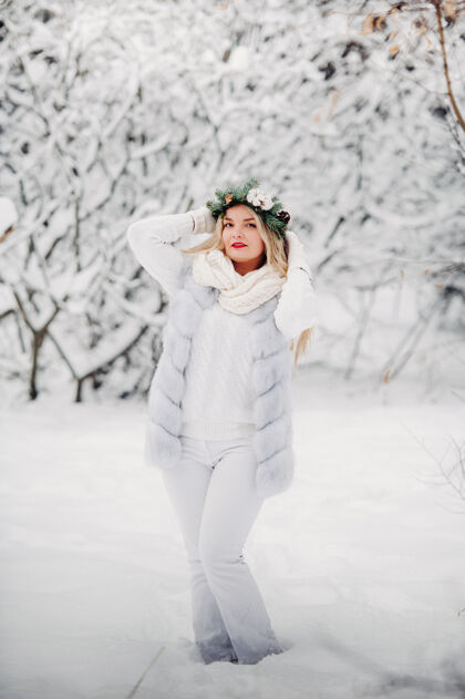 人一个穿着白衣服的女人在寒冷的冬天的照片森林女孩她头上戴着花圈在冰雪覆盖的冬季森林里雪花风景冬季森林