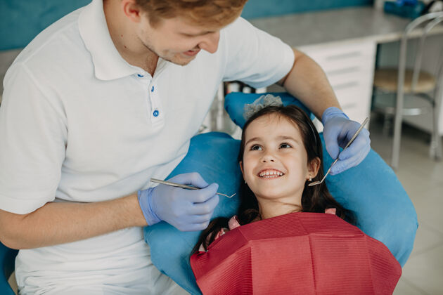 牙科美丽的小女孩坐在口腔科的椅子上 看着她的牙医微笑着做牙齿手术年轻牙科微笑