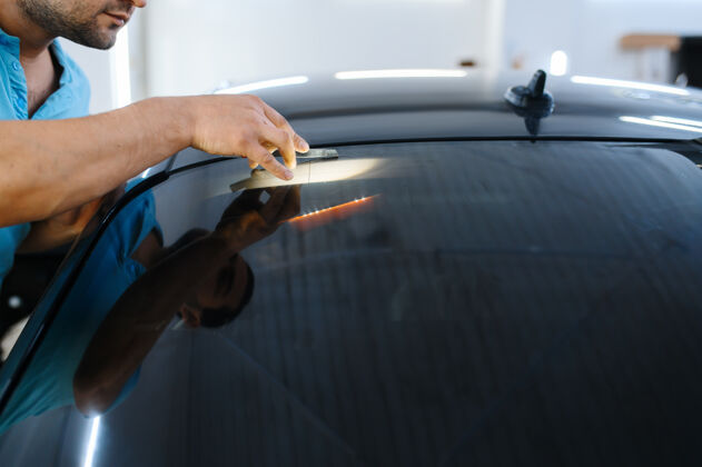 工艺男包装安装汽车染色 调整服务工人在车库的车窗上涂乙烯基色 有色汽车玻璃人汽车工业