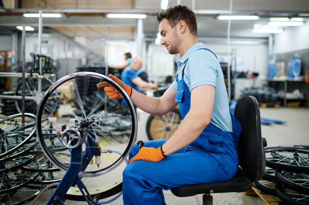 机器机床上的男工人正在检查自行车的轮辋工厂自行车车轮在车间装配轮胎齿轮工业
