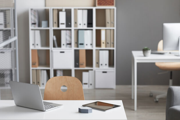 工作空旷的工作场所 笔记本电脑和书柜在现代办公室的背景下电脑笔记本电脑空置