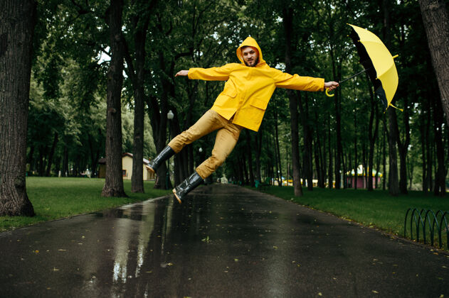 橡胶风雨交加夏日公园打伞人白天男性穿着雨衣和胶靴的人 巷子里天气潮湿夏天家伙人
