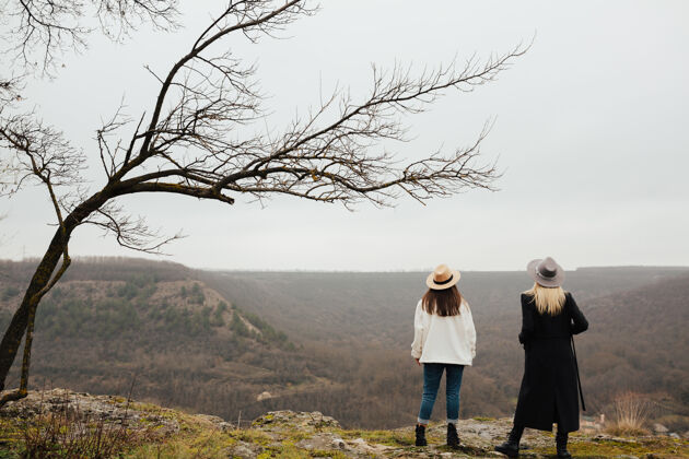 休闲两个女孩在山顶上看全景放松山谷远足者