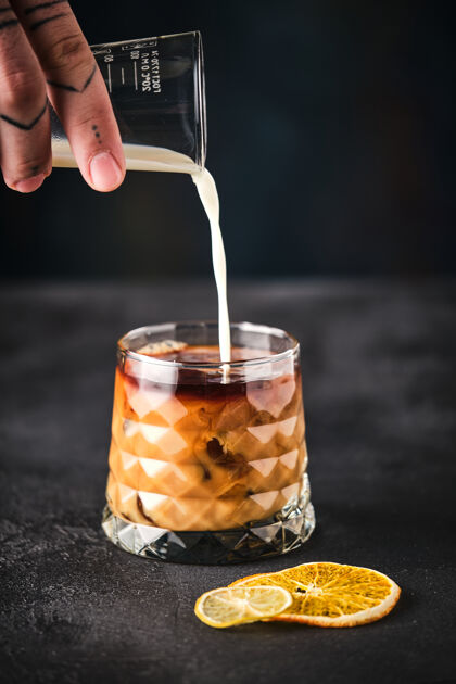 冰咖啡装饰有橙色雄性手把牛奶和咖啡一起倒进杯子里酒精牛奶鸡尾酒