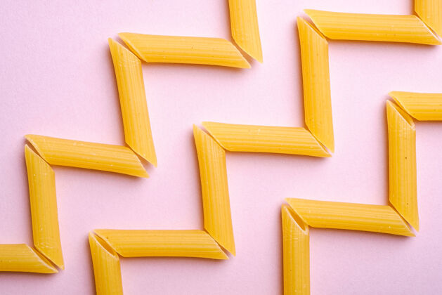 饮食意大利通心粉 生潘尼管通心粉之字形图案在粉红色墙上 俯视图 抽象食物传统特写生的