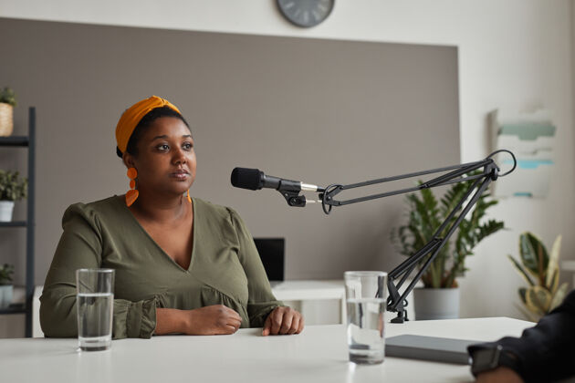 商务女性一位年轻的超重妇女坐在桌子旁用麦克风讲话 接受电台采访严肃面试工作