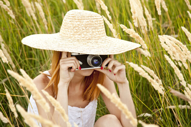 乡村在草地上拿着旧相机的红发女孩绿色田野情感