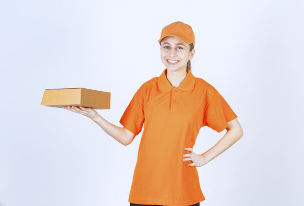 年轻人穿着黄色制服的女信使送一个纸板箱食品安全服务