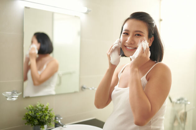 怀孕孕妇在浴室水槽上方用水溅脸中国洗镜子