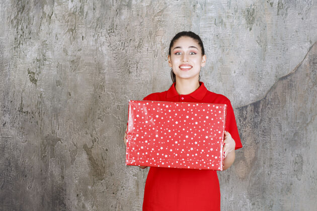 年轻人一个十几岁的女孩手里拿着一个有白点的红色礼盒工人人体模特模特