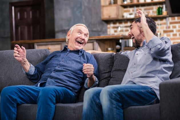 爱快乐的老人和他的儿子在家休息 一边讲笑话沙发儿子关系