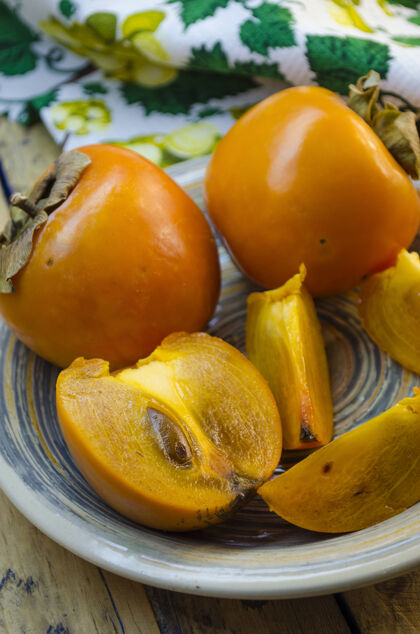 沙漠成熟的柿子放在木桌上的盘子里树叶水果健康