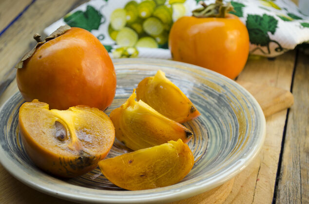 有机成熟的柿子放在木桌上的盘子里水果午餐自然