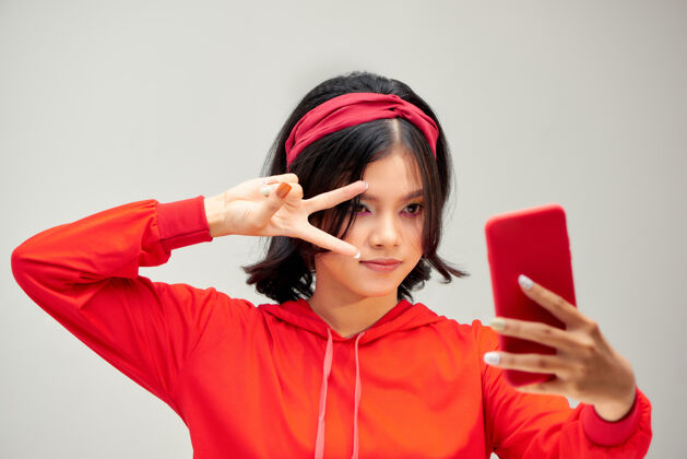 中国一个年轻漂亮的女人在智能手机上自拍的照片 背景是白色的彩虹亚洲自拍