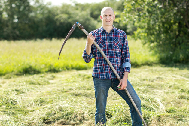 后院男人用镰刀用老式的方式割草生态男性农场