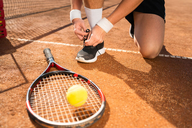 鞋网球运动员边打边系鞋带腿球拍运动