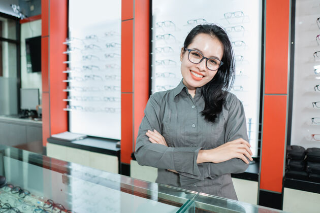 医学在眼科诊所里 一位戴眼镜的美女在眼镜陈列柜的背景下摆姿势挑选验光亚洲