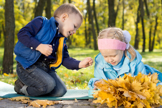 放松可爱的弟弟妹妹在秋天的森林里玩耍 采集黄色的秋叶娱乐季节休闲