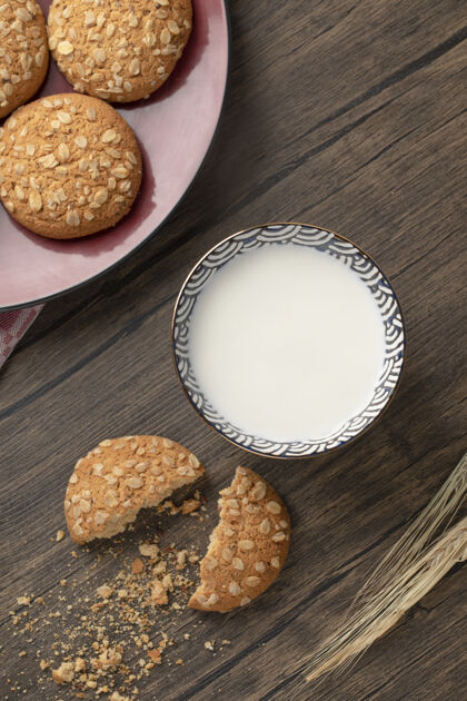 谷物红盘子上放着燕麦片饼干和一碗鲜奶放在木桌上谷类燕麦自制