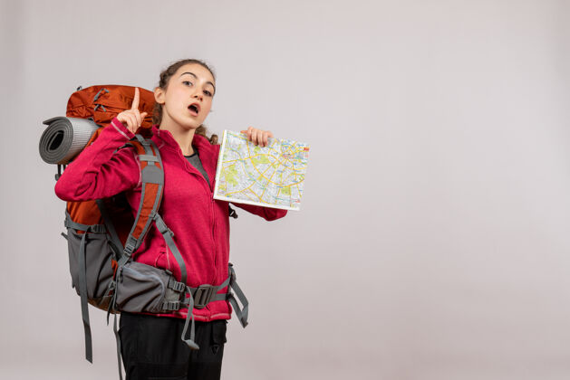 旅游正面图年轻的旅行者拿着大背包拿着地图手指向上地图年轻的旅行者背包