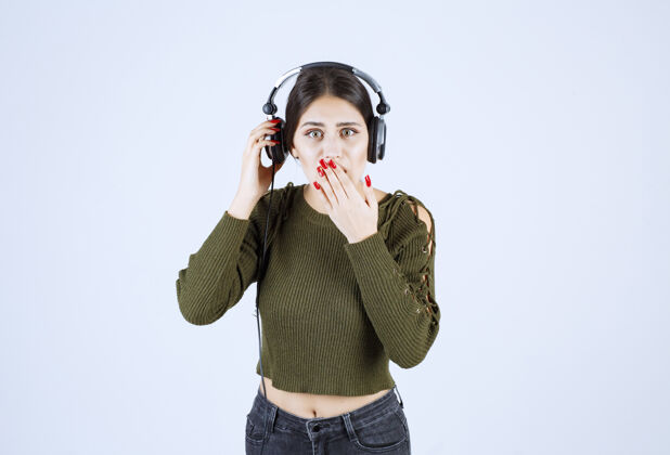 年轻一幅富有表现力的年轻女孩的画像 她在听音乐 捂着嘴耳机人女性