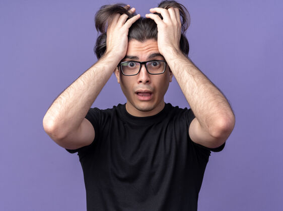 人一个穿着黑色t恤 戴着眼镜的年轻帅哥吓得把头发孤立在紫色的墙上衣服男人眼镜