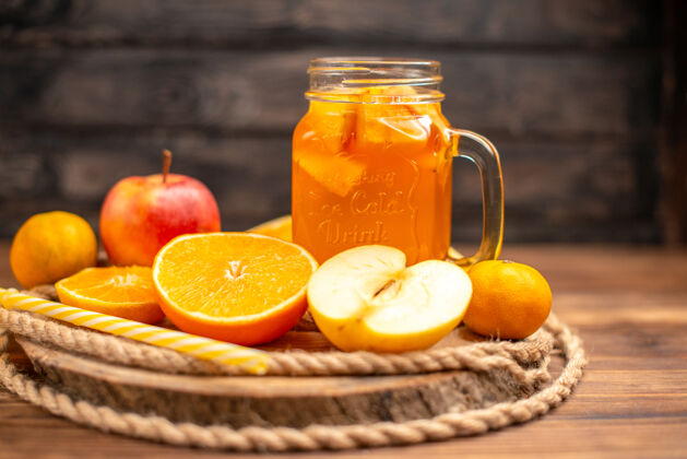管侧视图有机新鲜果汁在一个瓶子与管和水果在砧板和棕色的木桌上服务水果柠檬果汁