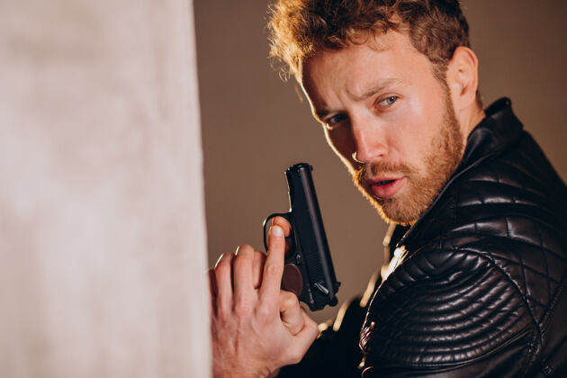 犯罪帅哥演员拿着武器在演播室摆姿势暴力强壮保安
