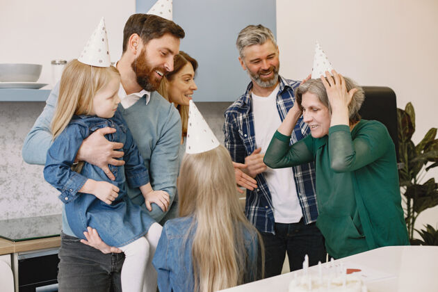 孩子一家人和他们的两个女儿都有一个庆祝祖母生日的聚会父母帽子吹