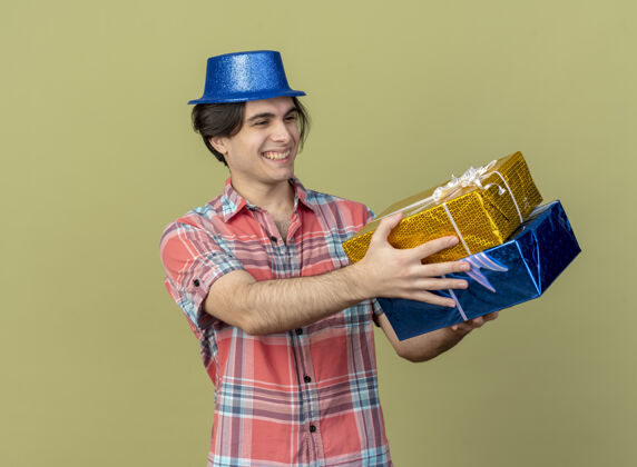 盒子面带微笑的白人帅哥戴着蓝色派对帽拿着礼物盒看聚会蓝色帽子