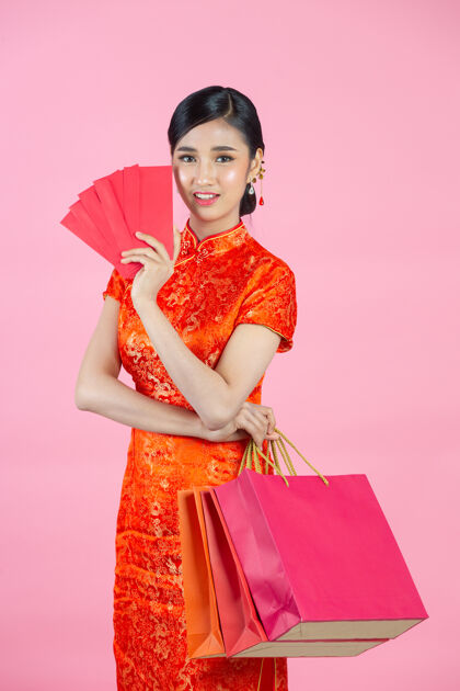 女人美丽的亚洲女人快乐的微笑和购物在中国新年的粉红色背景购物女孩中文