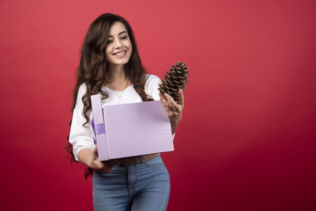 女孩美丽的女人拿着紫色的礼物盒 看着松果高质量的照片礼物女士女人