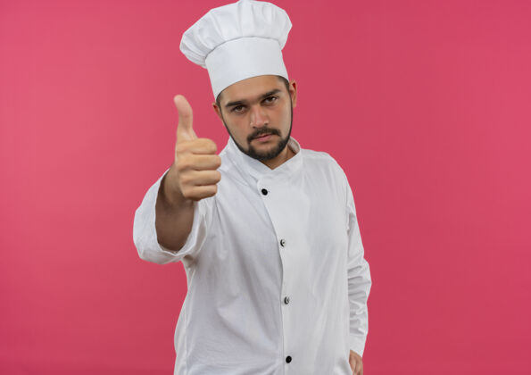 男性自信的年轻男性厨师身着厨师制服 在粉色墙壁上展示大拇指 并留有复印空间展示自信年轻
