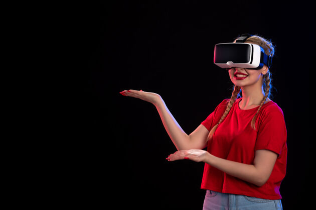 虚拟现实年轻女性在黑暗的墙上玩虚拟现实的正面图正面年轻女性游戏