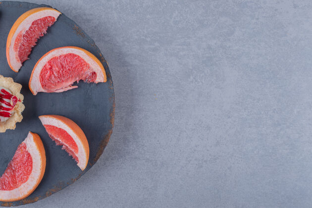 填充新鲜柚子片配饼干放在灰色的木盘上烘焙形状木头