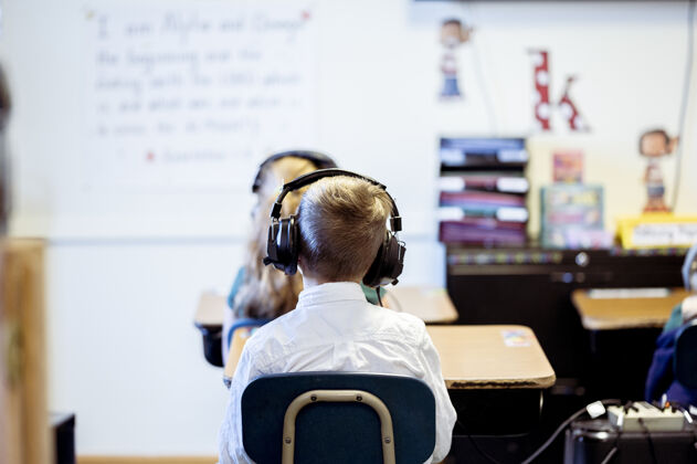 教育一个戴着耳机坐在教室里的孩子的选择性聚焦镜头可爱男孩孩子
