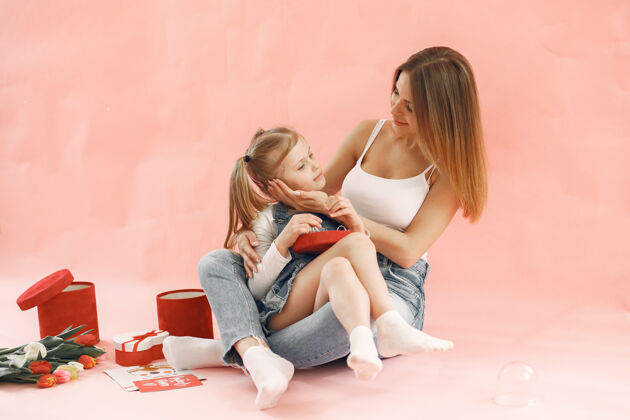 愛媽媽和女兒坐在一起粉紅色的墻母親節的概念擁抱母親節母親