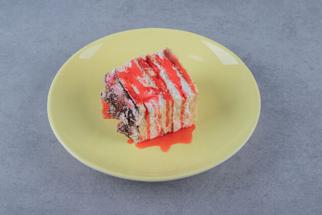 烘焙新鲜的自制蛋糕片在黄色盘子上加上粉红色的酱汁房子饼干球体