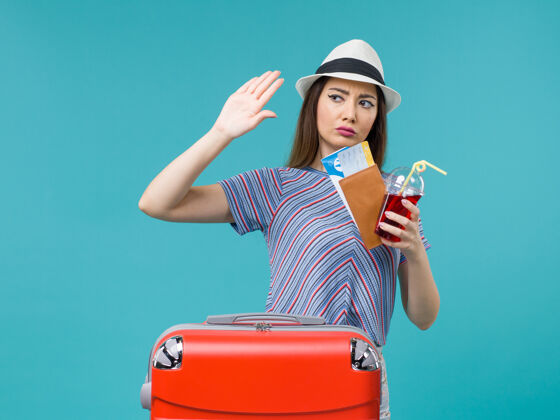 微笑前景度假中的女人拿着果汁拿着蓝色背景的机票远航女海暑期飞机之旅果汁航程肖像