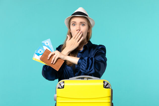 微笑前视图年轻女子拿着机票 准备在蓝色背景上度假海上旅行航程飞机度假人成人肖像