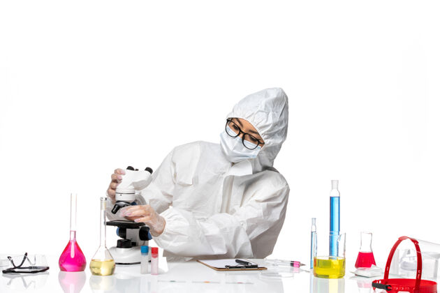 专业正面图身着特殊防护服的年轻女化学家在白色背景上固定显微镜病毒实验室共价健康化学病毒防护医生