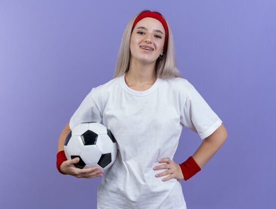 头带微笑的年轻白人运动女孩戴着背带和头带运动型背带球
