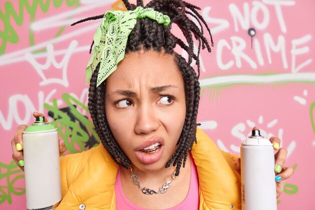 街道愤怒不满的特写镜头非裔美国少女把嘴唇集中在一边 留着可怕的发型 拿着喷雾瓶 在街上画创意画女人黄金城市
