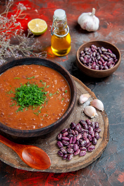 蔬菜木砧板上的番茄汤豆大蒜和混色桌上的油瓶俯视图瓶子汤食物