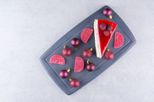 块深色盘子上有糖果和圣诞球的芝士蛋糕高质量照片糖果美味糕点