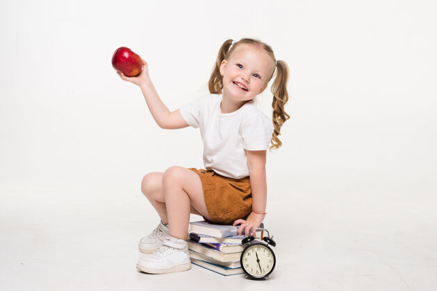 女学生抱着苹果的小女孩孤零零地坐在一堆书上时钟女孩学校