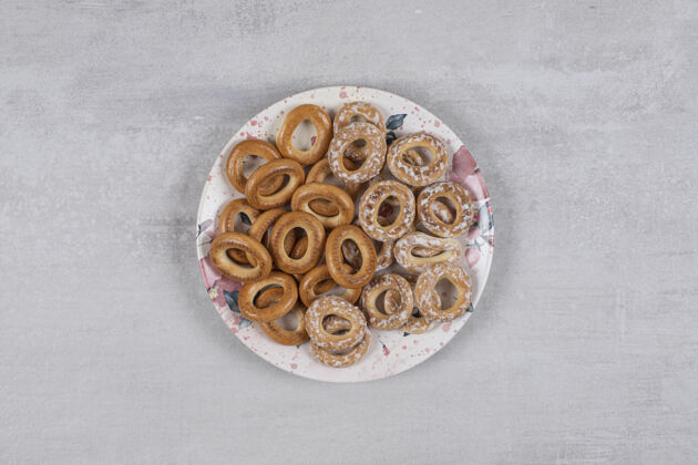 饼干白色盘子上有两种美味的椒盐脆饼圈面包房干的饼干